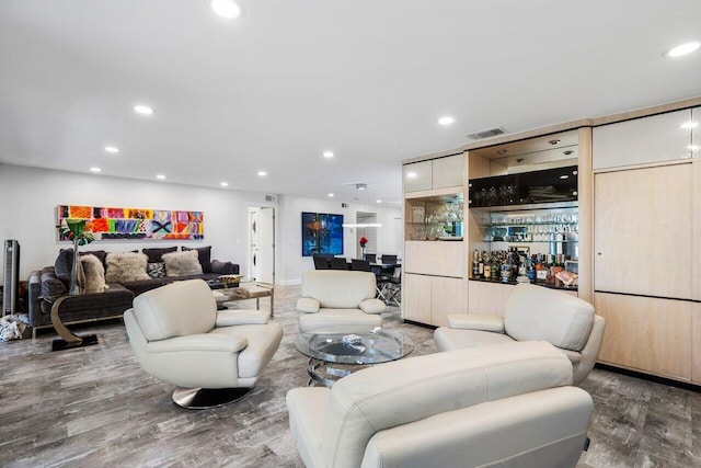 living room with recessed lighting, visible vents, a dry bar, and wood finished floors