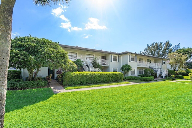 townhome / multi-family property featuring a front lawn, stairway, and stucco siding