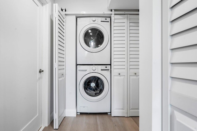 laundry room featuring stacked washer and dryer, wood finished floors, and laundry area