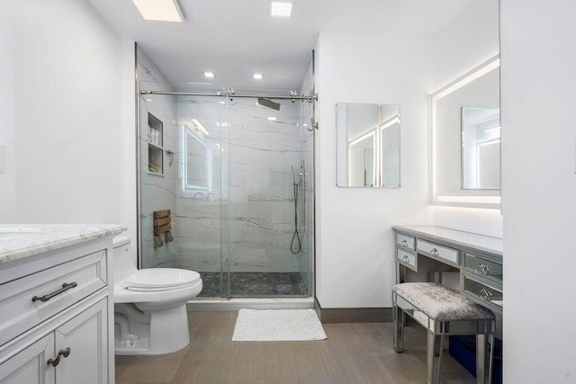 bathroom featuring a marble finish shower, baseboards, vanity, and toilet