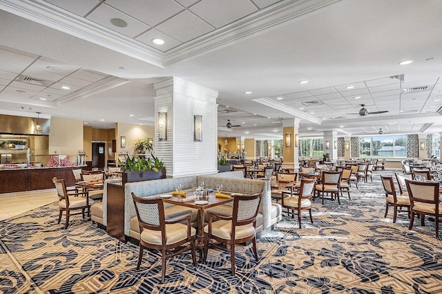 dining space with light tile patterned floors, a raised ceiling, a ceiling fan, ornamental molding, and ornate columns