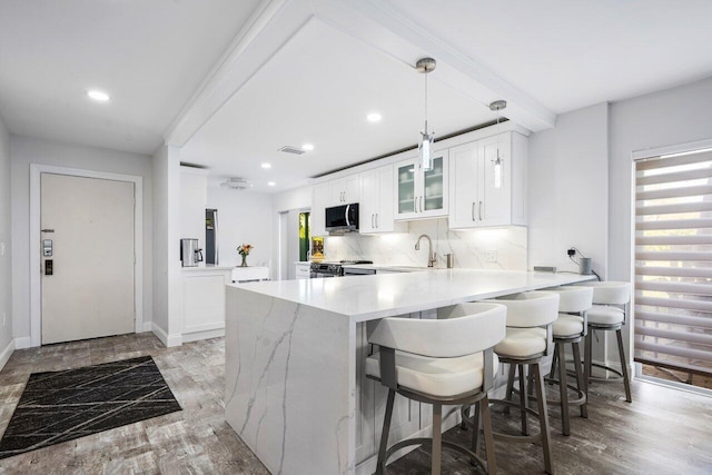 kitchen featuring stainless steel appliances, tasteful backsplash, a peninsula, and light wood-style floors