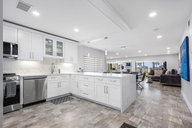 kitchen with a peninsula, a sink, visible vents, light countertops, and appliances with stainless steel finishes