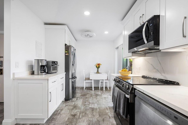 kitchen featuring appliances with stainless steel finishes, white cabinetry, light wood-style floors, and decorative backsplash