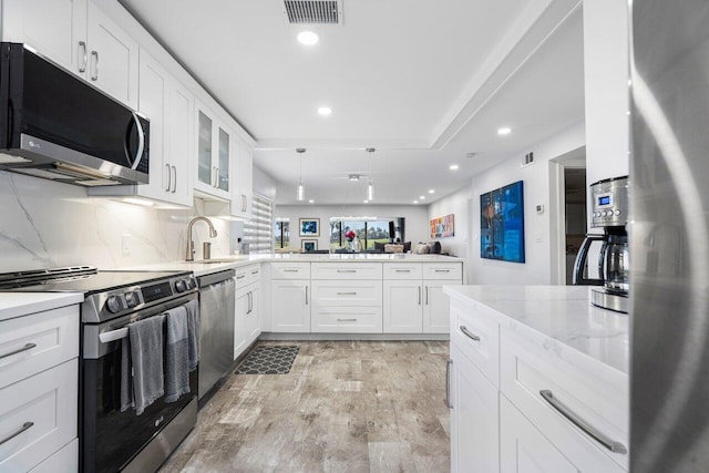 kitchen featuring visible vents, light wood-style flooring, appliances with stainless steel finishes, a peninsula, and a sink