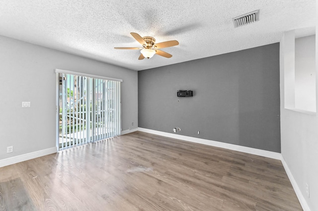 spare room with visible vents, a textured ceiling, wood finished floors, baseboards, and ceiling fan