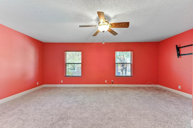 carpeted empty room featuring baseboards, a textured ceiling, and a ceiling fan