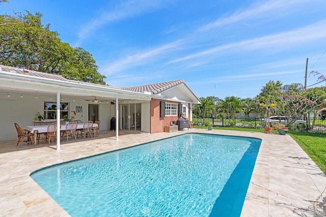 view of swimming pool featuring a patio area, a fenced in pool, fence, and a ceiling fan