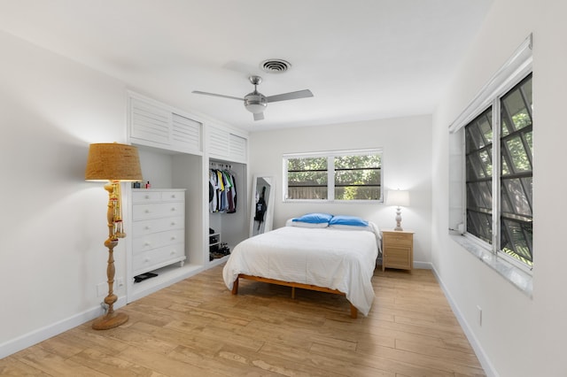 bedroom featuring a closet, visible vents, light wood-style floors, a ceiling fan, and baseboards