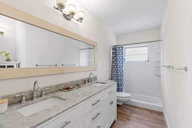 bathroom featuring double vanity, toilet, a sink, and wood finished floors