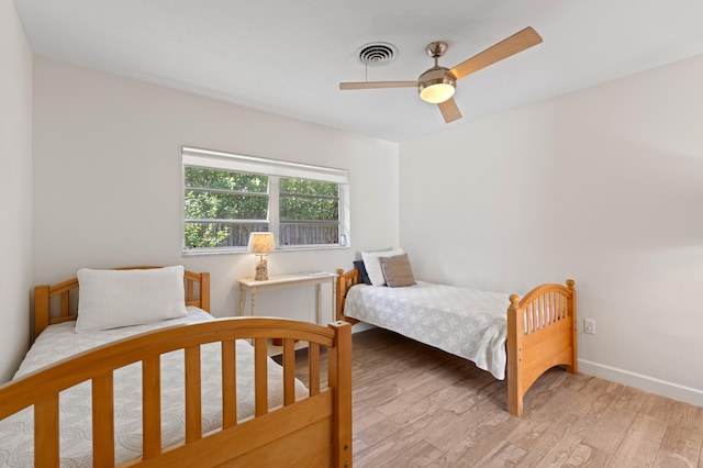 bedroom featuring baseboards, ceiling fan, visible vents, and light wood-style floors