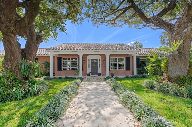 view of front of house with covered porch, brick siding, and a tiled roof