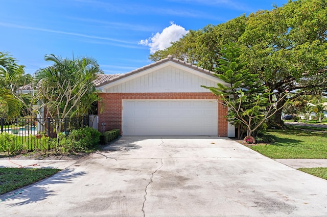 view of front of property with a garage, brick siding, driveway, and fence