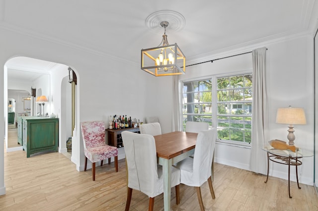 dining area featuring arched walkways, crown molding, baseboards, light wood finished floors, and an inviting chandelier