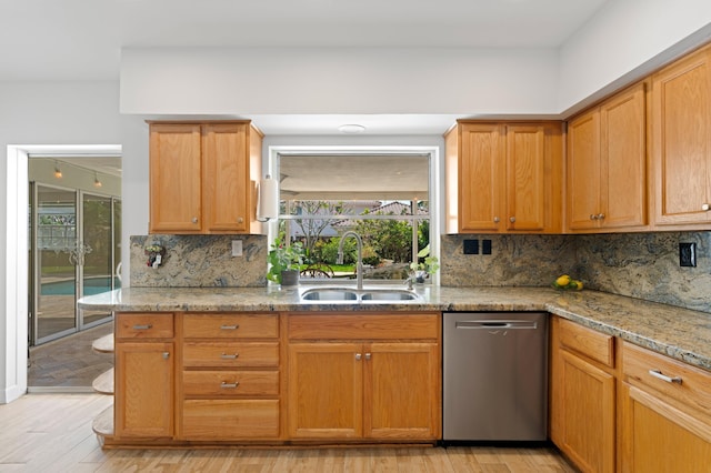 kitchen featuring a sink, light stone countertops, light wood finished floors, and stainless steel dishwasher