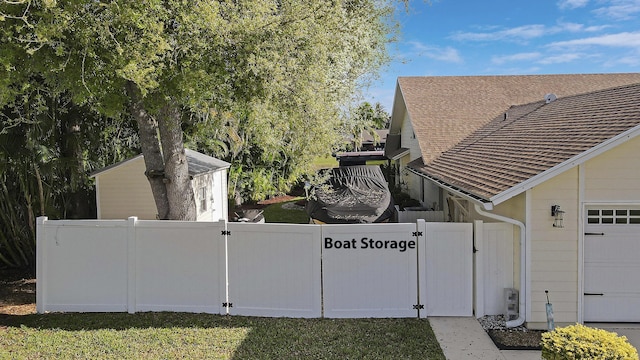 view of side of property with a garage, fence, a lawn, roof with shingles, and a gate