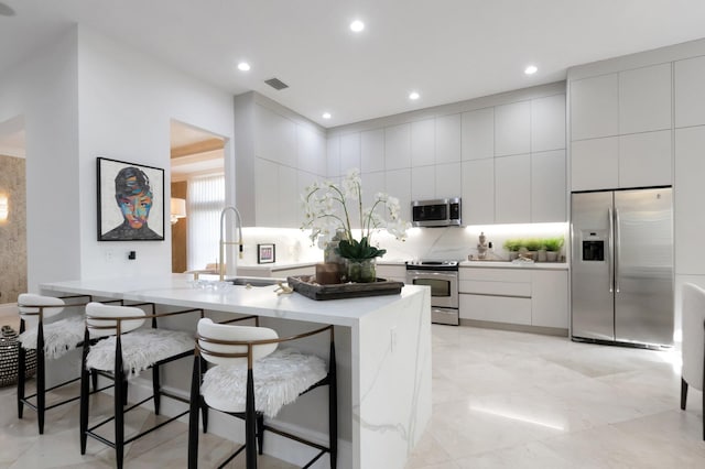 kitchen with visible vents, a kitchen bar, modern cabinets, stainless steel appliances, and light countertops