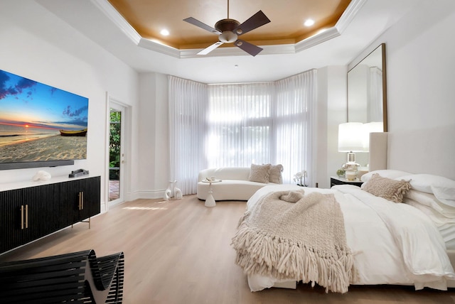 bedroom featuring wood finished floors, a tray ceiling, and ornamental molding