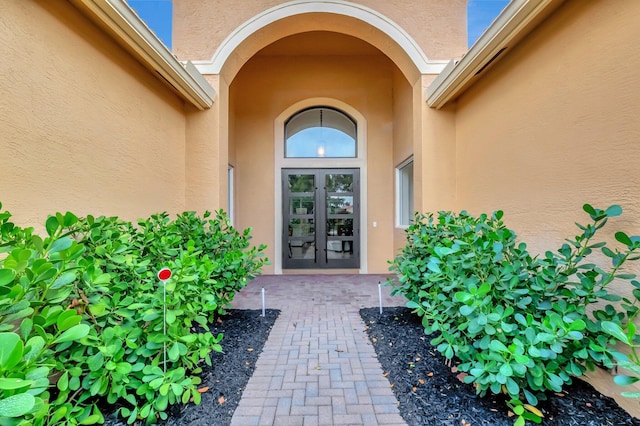 view of exterior entry with french doors and stucco siding