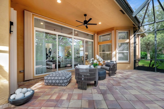 view of patio / terrace featuring an outdoor living space, glass enclosure, and ceiling fan