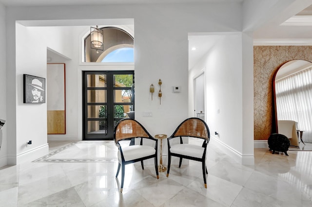 interior space with baseboards, marble finish floor, ornamental molding, and a towering ceiling