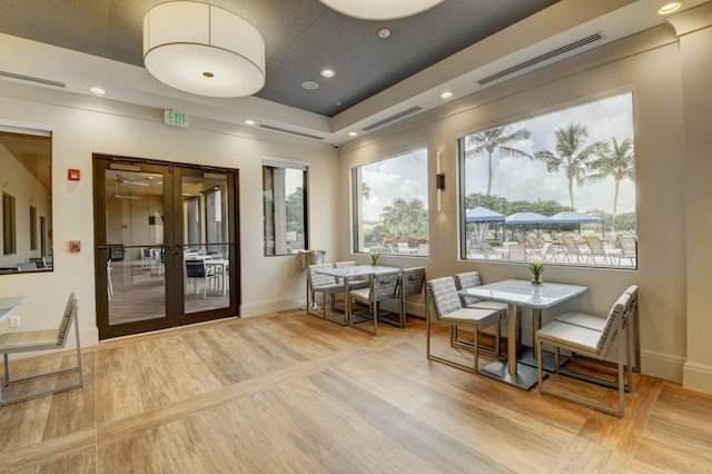 interior space featuring visible vents, a tray ceiling, wood finished floors, recessed lighting, and french doors