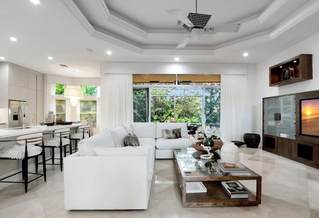 living room with a raised ceiling, crown molding, recessed lighting, and ceiling fan