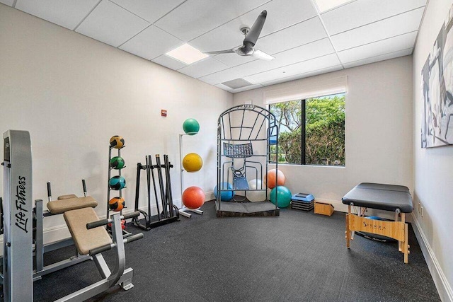 exercise room with a drop ceiling, baseboards, and a ceiling fan