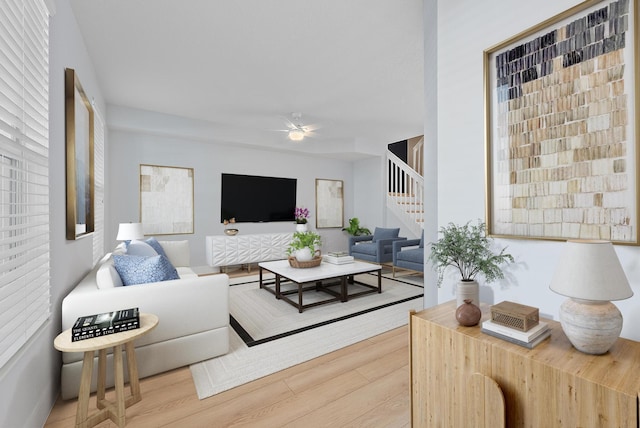 living area with stairs, wood finished floors, and ceiling fan