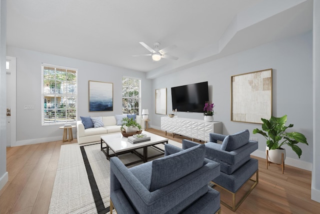 living room with ceiling fan, baseboards, and wood finished floors