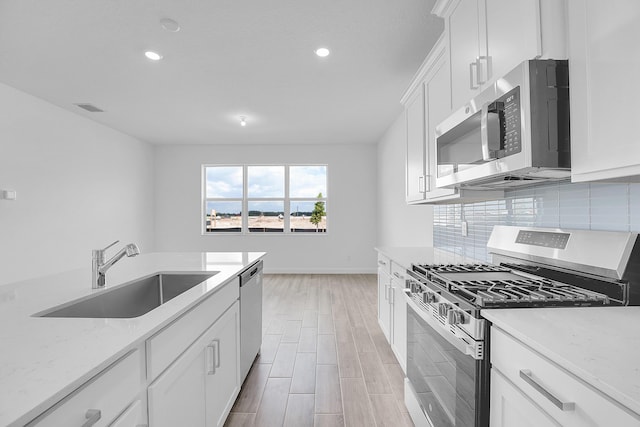 kitchen featuring visible vents, decorative backsplash, stainless steel appliances, white cabinetry, and a sink