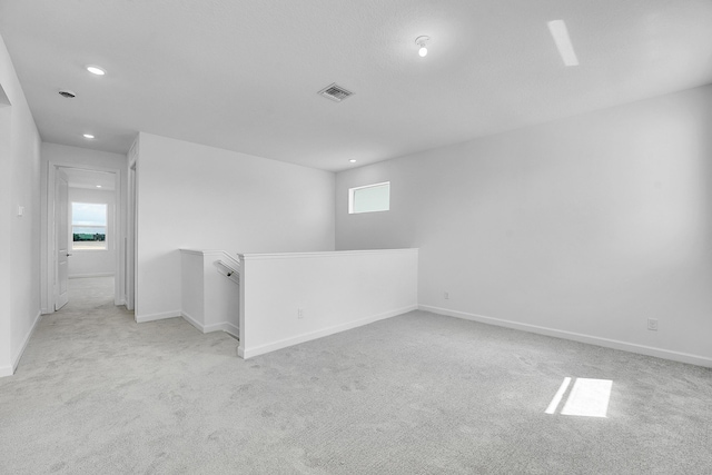 empty room with light colored carpet, visible vents, plenty of natural light, and baseboards