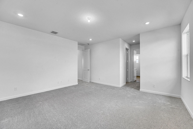 carpeted spare room featuring a wealth of natural light, recessed lighting, visible vents, and baseboards