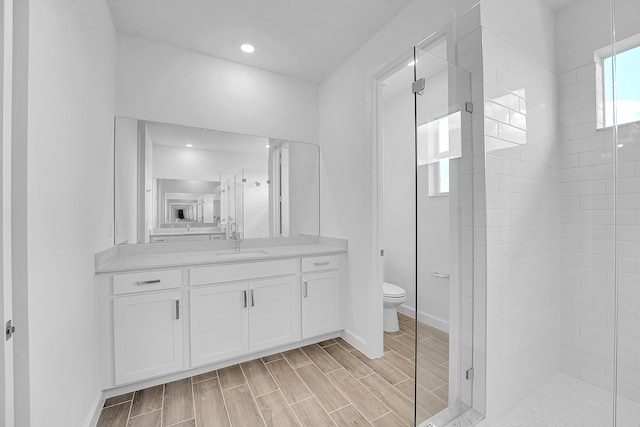 bathroom featuring a stall shower, wood finish floors, vanity, and toilet