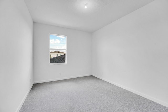 carpeted spare room featuring baseboards