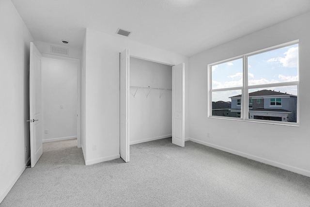 unfurnished bedroom with a closet, carpet flooring, visible vents, and baseboards