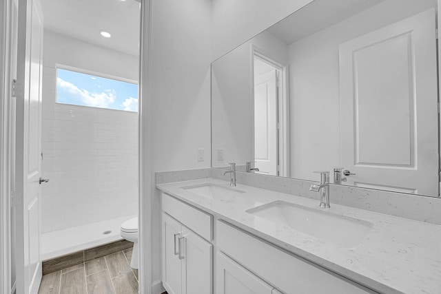 bathroom with a sink, a shower stall, toilet, and double vanity