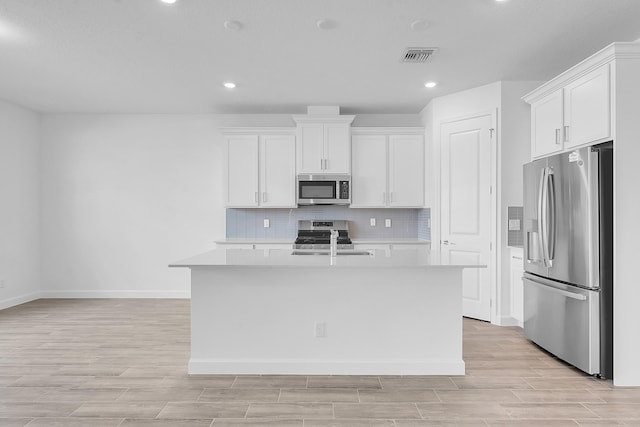 kitchen with appliances with stainless steel finishes, white cabinets, light countertops, and backsplash