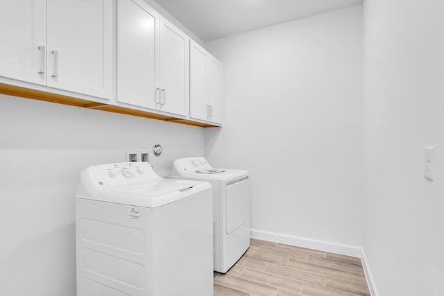 laundry room featuring wood finish floors, cabinet space, independent washer and dryer, and baseboards