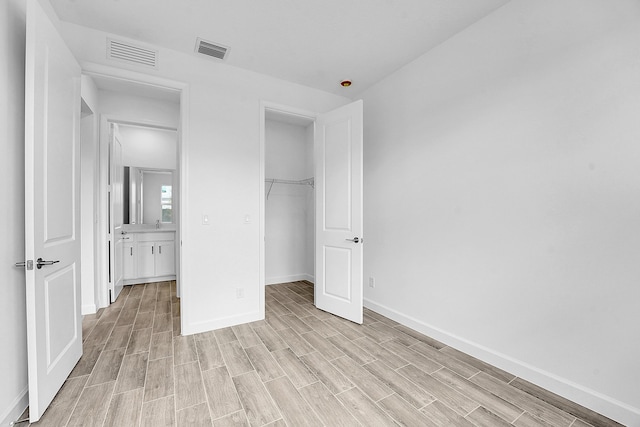 unfurnished bedroom featuring baseboards, a closet, visible vents, and wood tiled floor