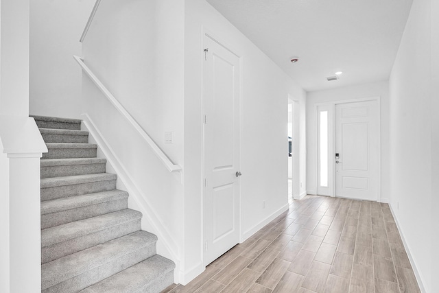 foyer with visible vents, baseboards, stairway, and light wood finished floors