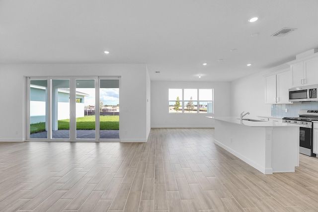 kitchen with visible vents, decorative backsplash, appliances with stainless steel finishes, light wood-style floors, and open floor plan