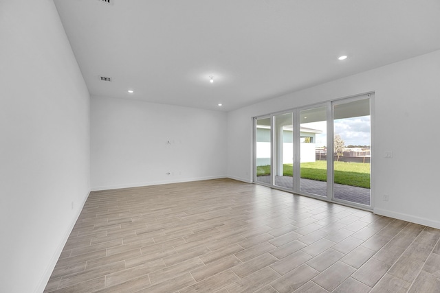 empty room with baseboards, light wood-type flooring, visible vents, and recessed lighting