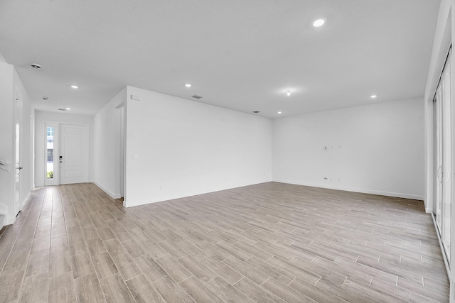 empty room featuring light wood finished floors, visible vents, and recessed lighting