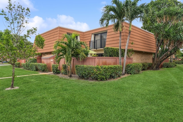 view of home's exterior with mansard roof, a lawn, and brick siding