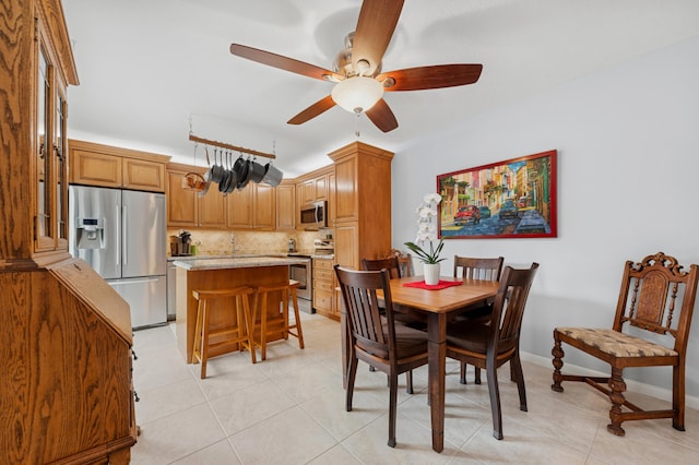 dining area with light tile patterned floors, ceiling fan, and baseboards