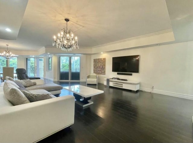 living area featuring a chandelier, a raised ceiling, plenty of natural light, and wood finished floors