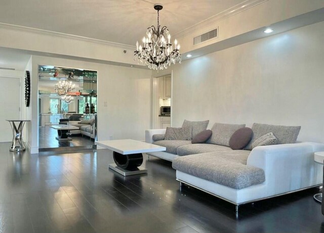 living area with ornamental molding, visible vents, a notable chandelier, and wood finished floors