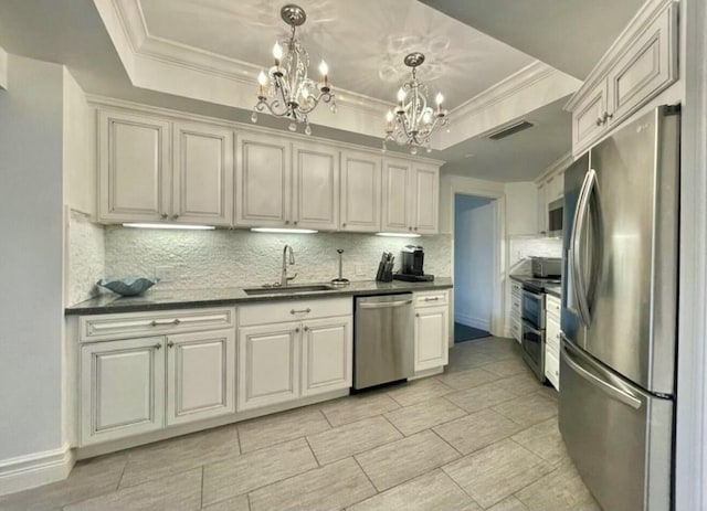 kitchen featuring visible vents, dark countertops, a tray ceiling, stainless steel appliances, and a sink