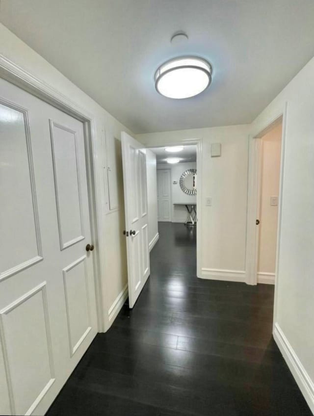 hall with dark wood-style floors and baseboards